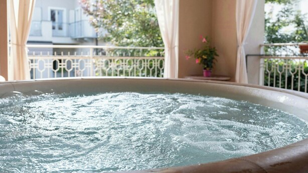 Un jacuzzi con vistas a un balcón y una casa al fondo.