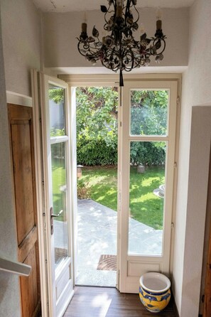 A doorway leading to a garden with a potted plant and a chandelier. - Grandmother's house with hot tub in Scurzolengo (Scurzolengo)