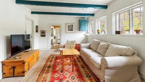 Uma sala de estar com televisão, sofá e tapete estampado.
