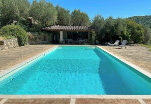 A rectangular swimming pool with clear blue water, surrounded by a stone deck. There is a covered patio area with outdoor furniture and a stone wall. - Historical panoramic villa with pool, Umbria (Perugia)