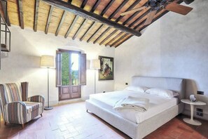 A bedroom with a large bed, a chair, a lamp, and a painting on the wall. - Tuscan estate with pool in the heart of Chianti (Impruneta)
