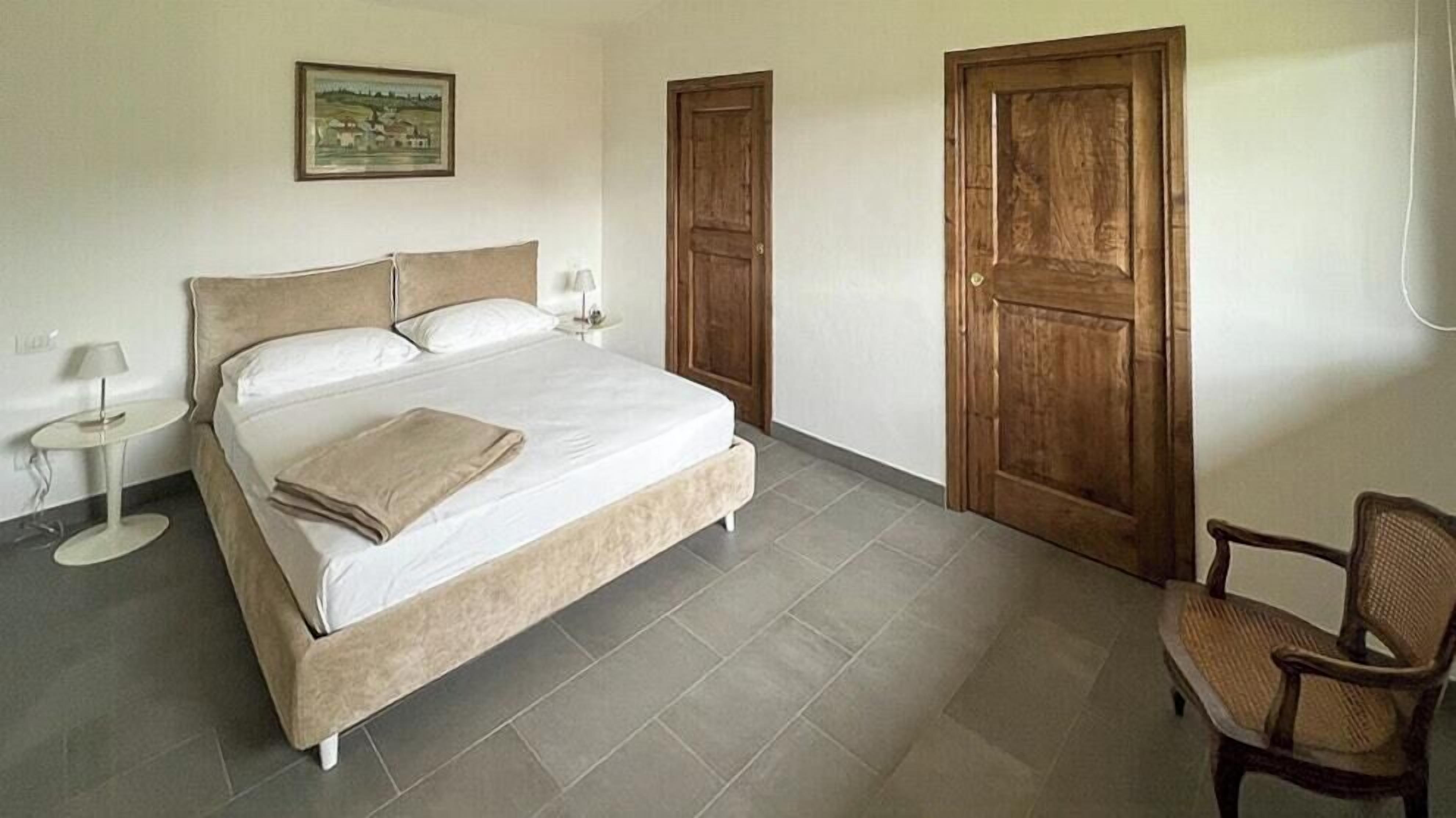 Ein Schlafzimmer mit einem Bett, einem Sessel, einem kleinen Tisch und zwei Türen.