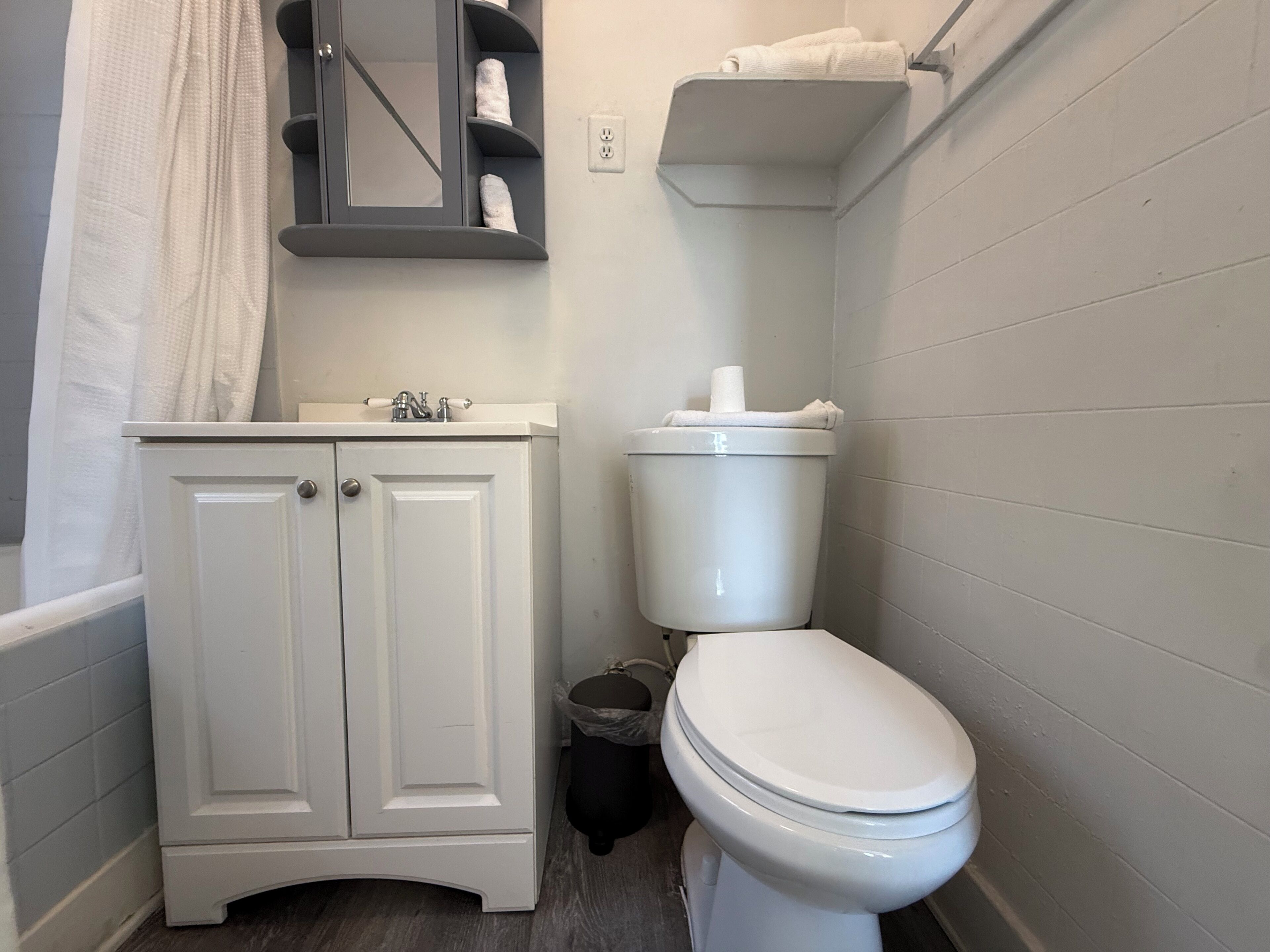 Un baño con inodoro blanco, lavamanos con espejo y un perchero para toallas.