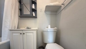 A bathroom with a white toilet, a sink with a mirror, and a towel rack. - Comfortable Studio Unit on 2nd Floor (Los Angeles)