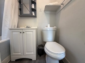 Ein Badezimmer mit Toilette, Waschbecken mit Spiegel und Handtuchhalter.