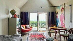 Un salon moderne avec un plafond en pente, un canapé rouge, une table à manger en bois et une grande fenêtre offrant une belle vue.