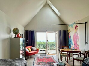 Ein modernes Wohnzimmer mit schrägverdeckter Decke, einem roten Sofa, einem Holzesstisch und einem großen Fenster mit Blick.