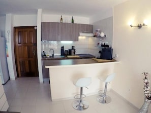 Eine moderne Küche mit Kochinsel, Barhocker und einer Holztür.
