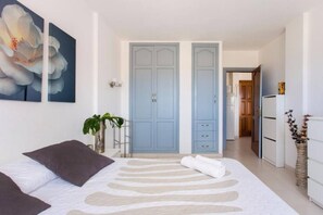 Ein Schlafzimmer mit einem Bett, einem großen blauen Kleiderschrank, einer weißen Kommode und einem Blumenbild.