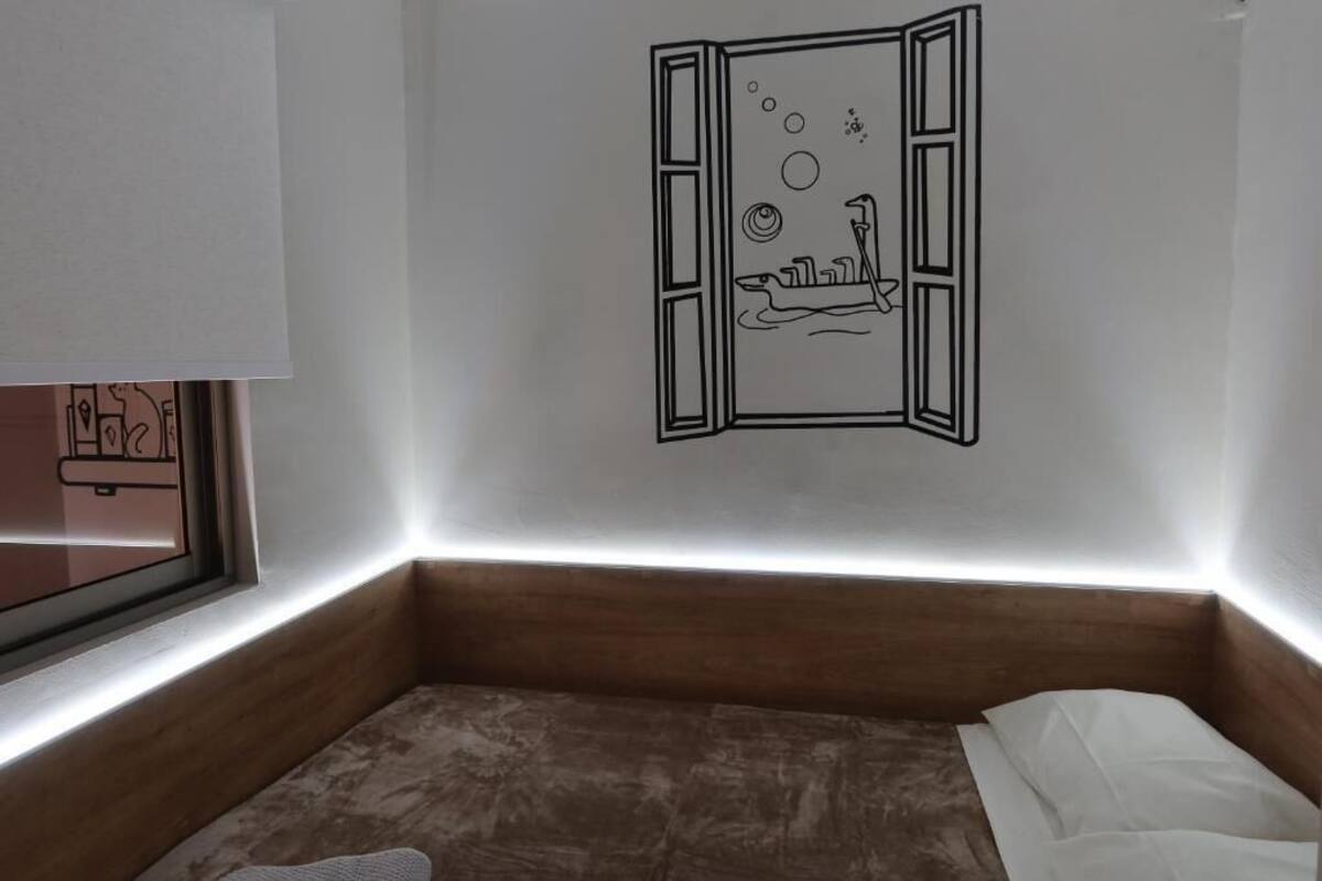 A bedroom with a bed, a window, and a wall decal of a ship.