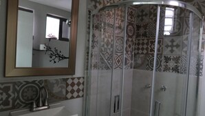 Un baño con cabina de ducha, lavabo y espejo.