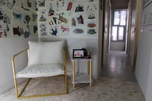 A room with a white sofa, a small table with a picture frame, and a wall decorated with various illustrations. - Casa Saratoga (Mexico City)