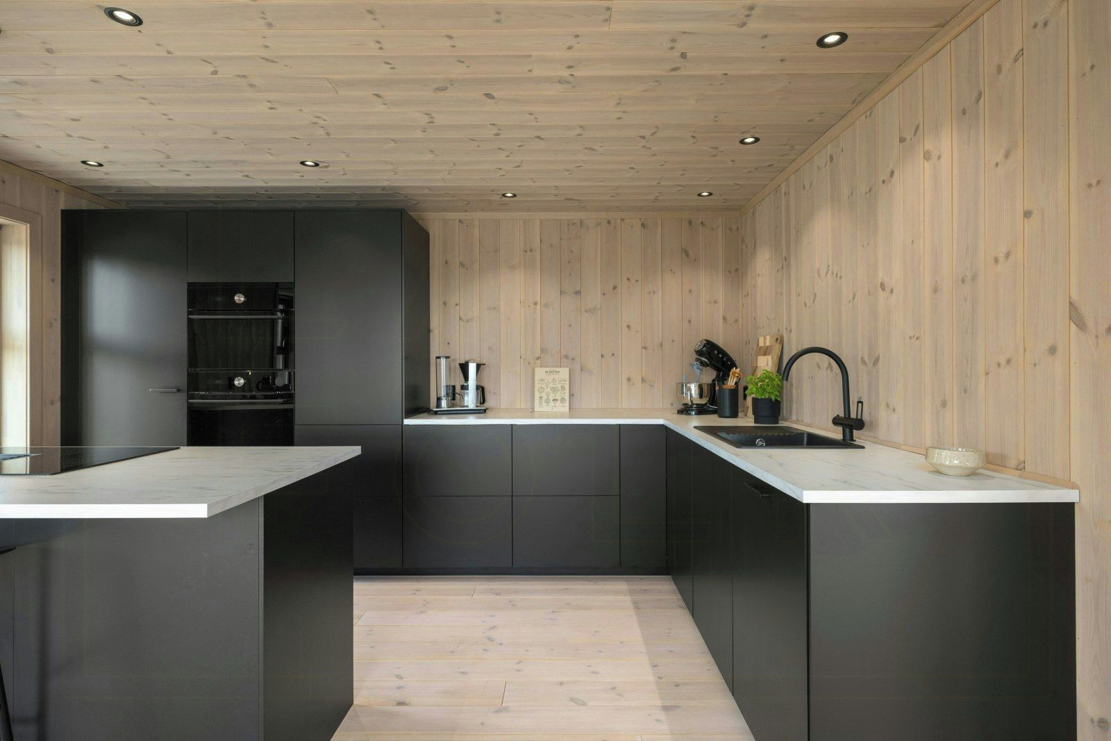 A modern kitchen with dark cabinetry, a wooden ceiling, and a central island with a sink.