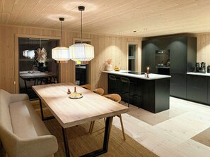 A modern kitchen with a central island, wooden ceiling, and pendant lighting. - Modern cabin with ski-in/out near Birken trails (Rena)