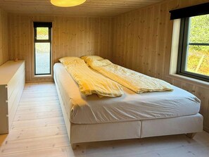 Een kamer met houten wanden, een bed, een raam en een bureau.