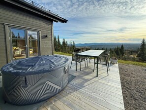 Een terras met een jacuzzi, een tafel en stoelen, met uitzicht op een prachtig landschap.