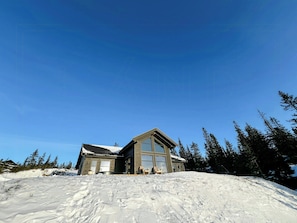 A lodge with a large window, a sloped roof, and a view of the surrounding forest. - Modern cabin with ski-in/out near Birken trails (Rena)
