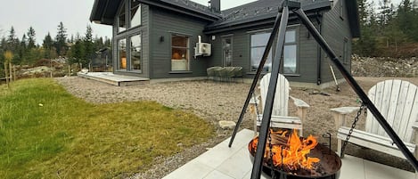 Une maison moderne avec un foyer extérieur dans le jardin.
