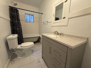 Ein Badezimmer mit Toilette, Badewanne, Dusche, Waschbecken und Spiegel.