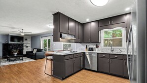 A modern kitchen with dark cabinets, stainless steel appliances, and a wooden floor. - Luxury Metro Atlanta Retreat - Sleeps 10 (Decatur)