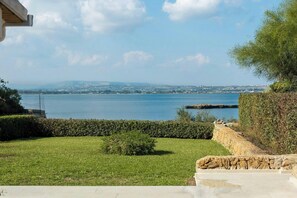 A coastal view with a grassy lawn, a stone wall, and a clear sky. - House with view of Ortigia and sea access (Siracusa)