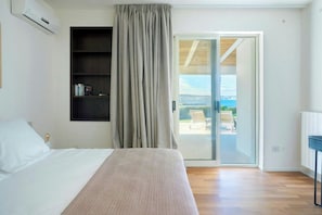 A bedroom with a bed, a built-in shelf, a sliding glass door to a balcony, and a view of the outdoors. - House with view of Ortigia and sea access (Siracusa)