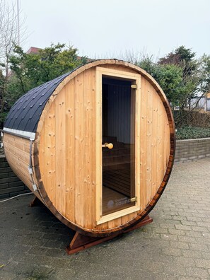 A wooden sauna with a curved roof, a door, and a small window. - Yellow beach house with sauna and view over Løkken (Løkken)