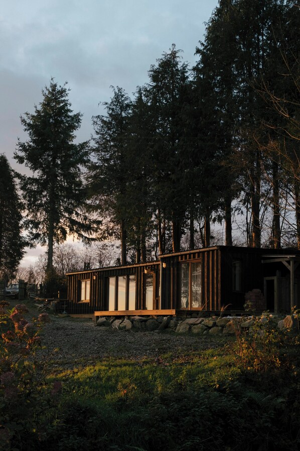 A cabin with a wooden deck, surrounded by dense forest. - Eco-friendly cabin in the Norman countryside (Gathemo)