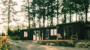 Eine Holzhütte mit einer Terrasse, einem Tisch und Stühlen, umgeben von Bäumen.