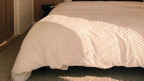 Ein Schlafzimmer mit Holzwand, einem Bett mit weißer Bettwäsche und zwei Wandleuchten.