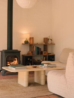A cozy living room with a fireplace, a bookshelf, and a comfortable sofa. - Eco-friendly cabin in the Norman countryside (Gathemo)