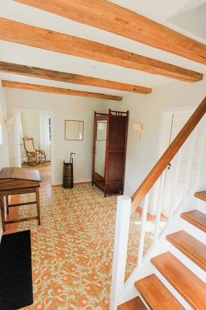 A room with a wooden staircase, a patterned floor, a chair, a table, and a mirror. - Experience the Uckermark from the old hayloft (Weggun)