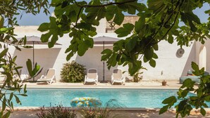 Area piscina con lettini, un cerchio galleggiante e un muro bianco sullo sfondo.