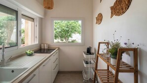 Una cucina con una finestra, un lavandino, un ripiano di legno con piante e uno scaffale a parete.