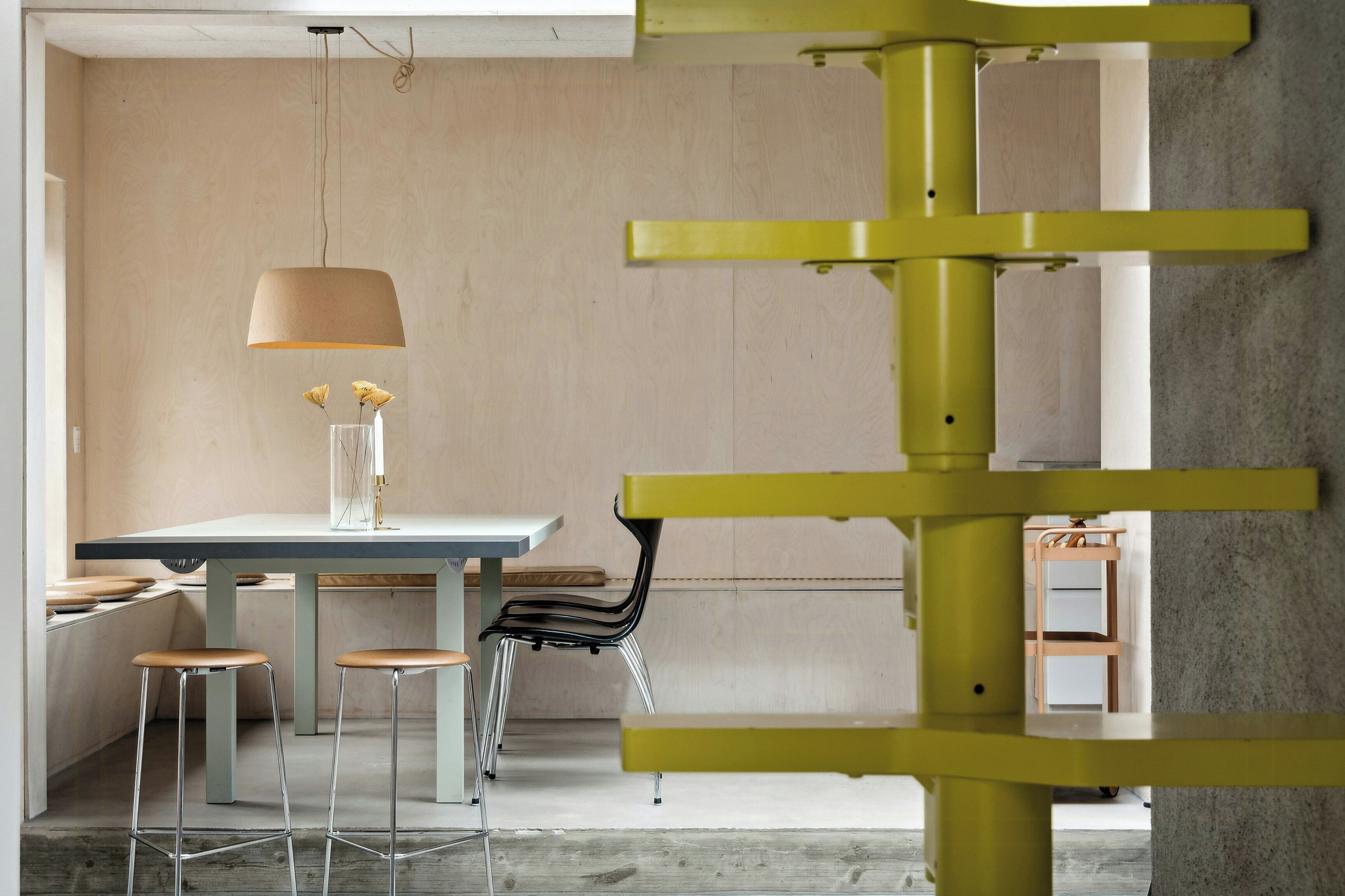 A modern interior with a dining area, bar stools, a table, and a unique yellow structure.