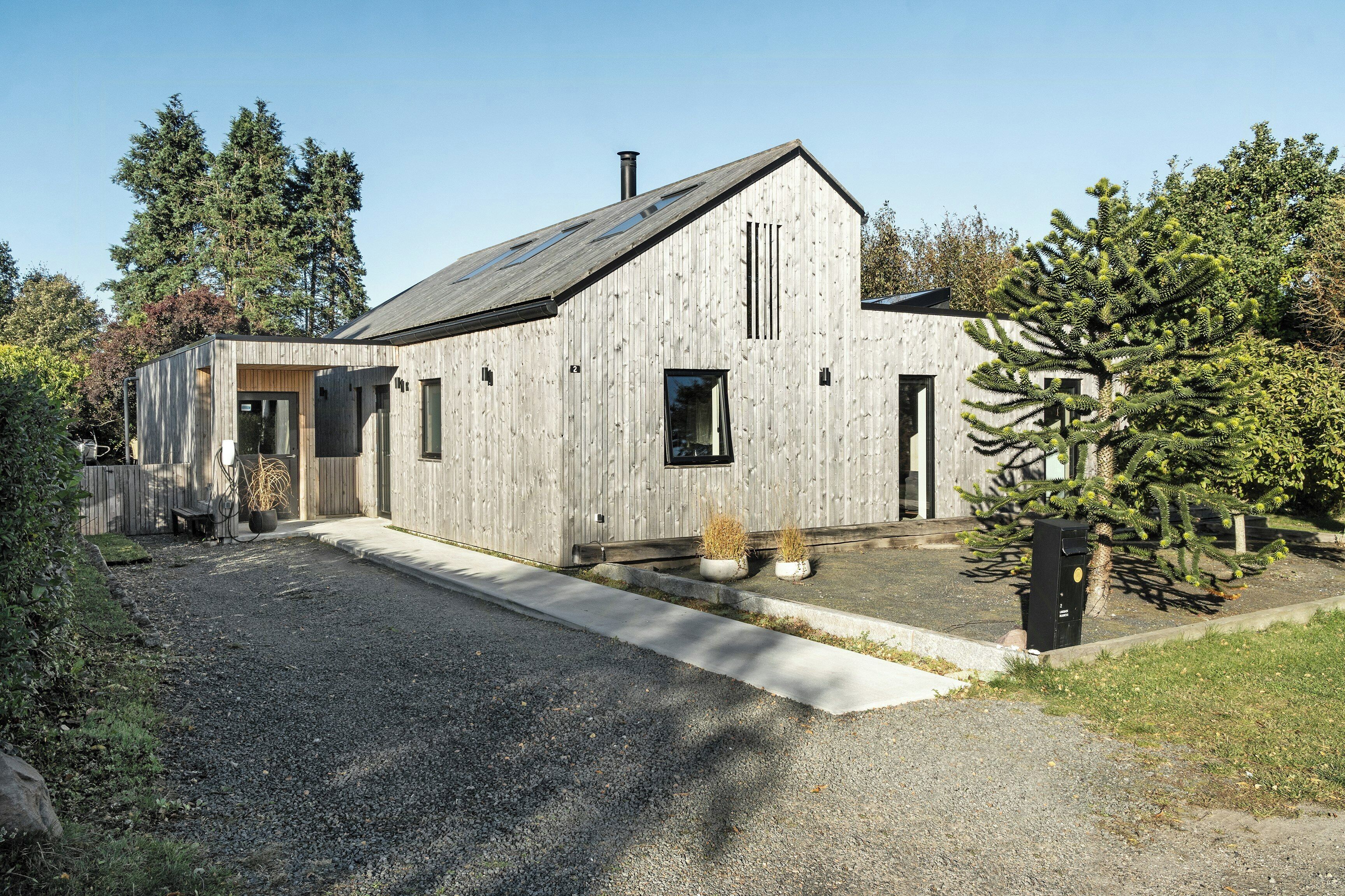 A modern wooden house with a sloped roof, a front door, and a small porch area.