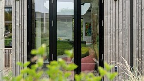 A modern building with a wooden exterior, large glass doors, and a visible outdoor seating area. - Nordic architecture with room for the whole family (Odder)