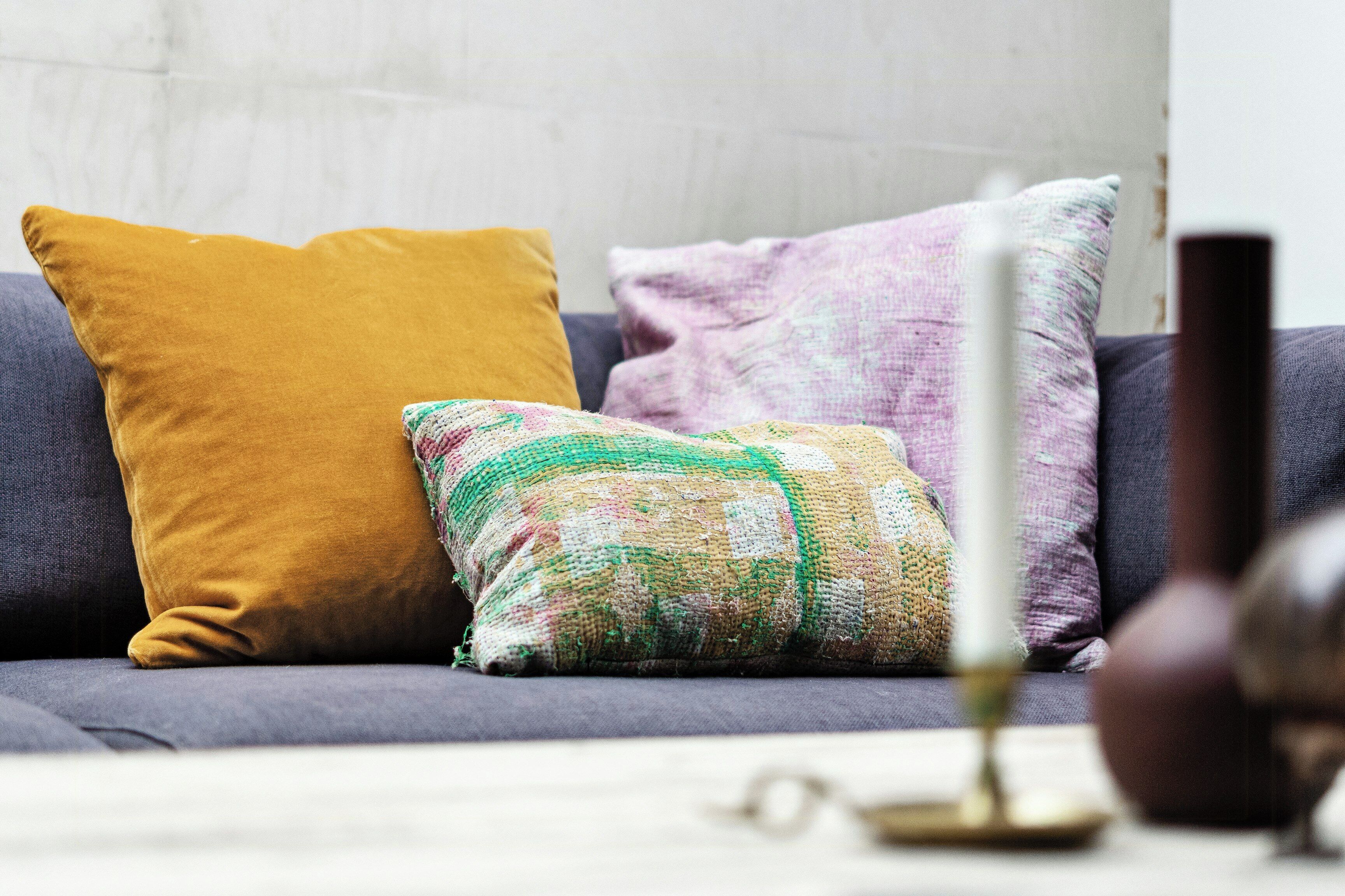 A sofa with three pillows, a vase, and a globe.