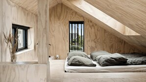 A bedroom with a sloped ceiling, a bed, a window, and a view of greenery outside. - Nordic architecture with room for the whole family (Odder)