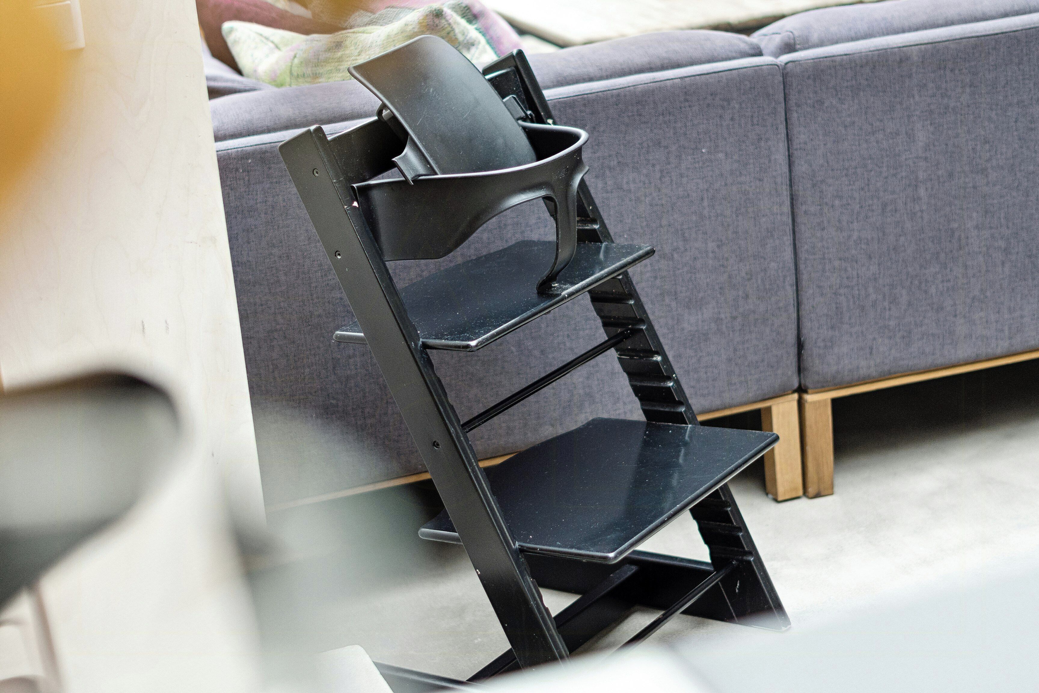 Una sedia moderna dal design originale, di fronte a un divano grigio.