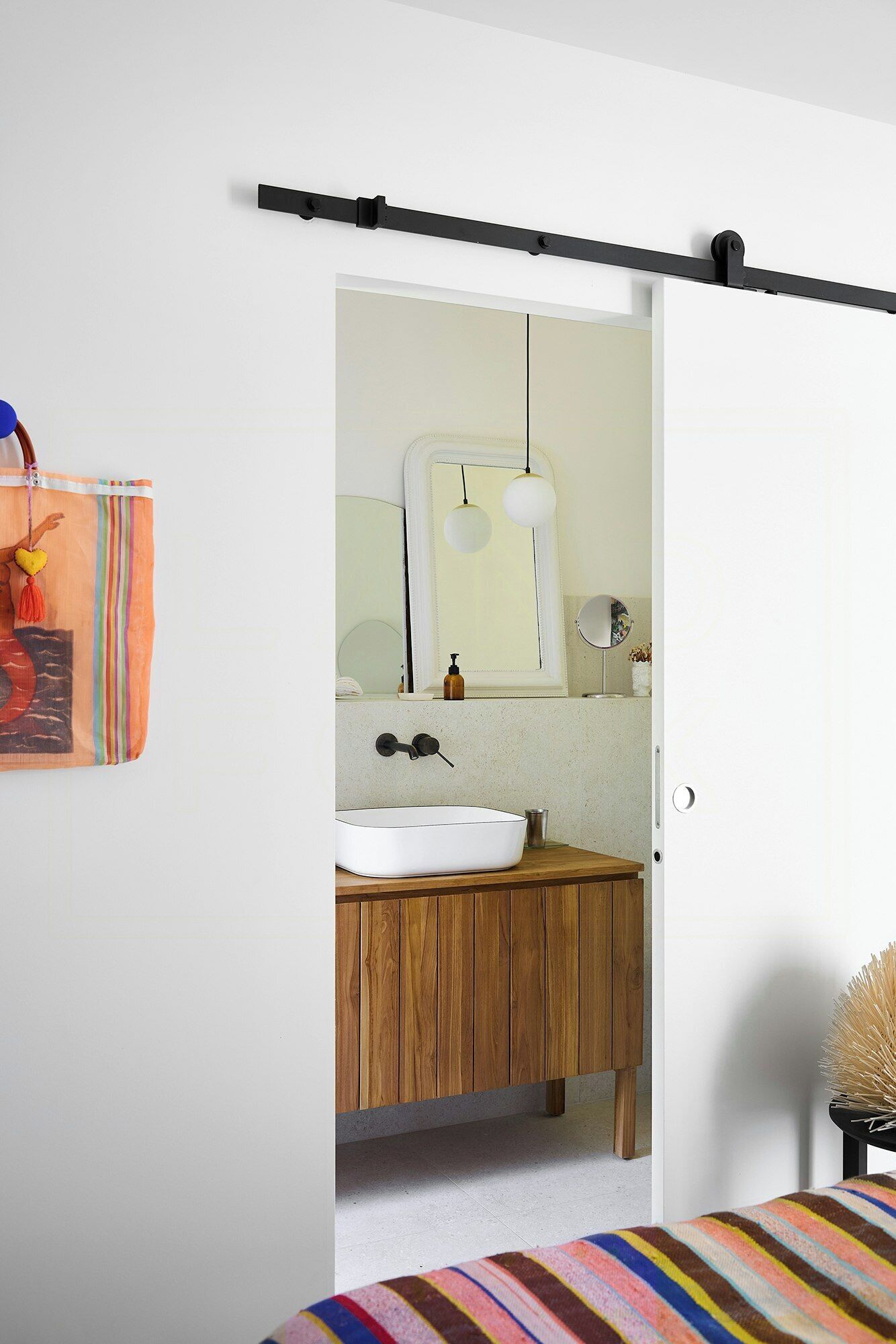 A bathroom with a wooden vanity, a white sink, a mirror, and a towel rack.