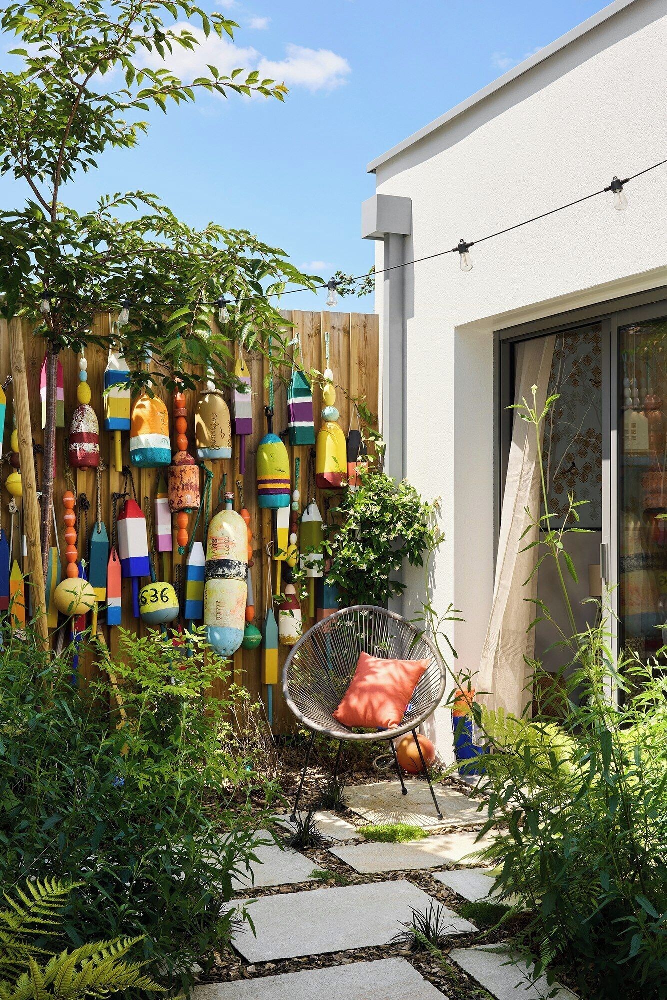 A garden with a wooden fence, a chair, and a potted plant.