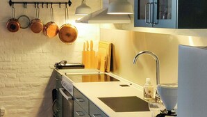 A modern kitchen with a wooden floor, white walls, and a built-in oven. - Apartment in renovated stable near UNESCO cliffs (Præstø)