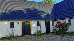 A building with a tiled roof, a central black door, and windows. - Apartment in renovated stable near UNESCO cliffs (Præstø)