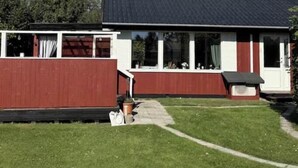 Una casa a un piano con tetto scuro, pareti esterne bianche e una sezione frontale rossa.