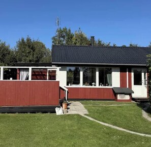 A single-story house with a dark roof, white exterior walls, and a red front section. - Holiday home in peaceful surroundings (Dannemare)