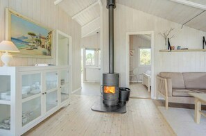 Ein Zimmer mit Kaminofen, einem weißen Schrank mit Glastüren, einem beigen Sofa und einem Bild an der Wand.