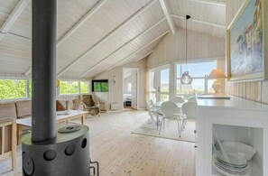 Ein geräumiges Zimmer mit hoher Decke, einem großen Fenster, einem Kamin, einem Essbereich und einem Fernseher.