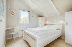 Ein Schlafzimmer mit Bett, Stuhl, Schreibtisch, Kleiderschrank und Fenster.