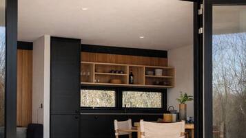 Une cuisine moderne avec des meubles en bois, un coin repas comprenant une table et des chaises, et une grande fenêtre.